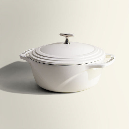 White enameled cast iron Dutch oven with a lid on a white background