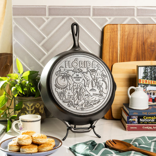 Cast iron skillet with 'Florida' engraving on a kitchen counter with books and a plant.