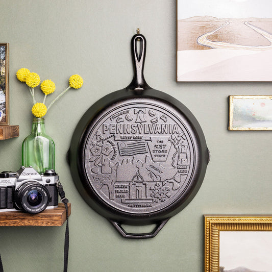 Decorative state cast iron skillet on a wall with framed pictures and a camera.
