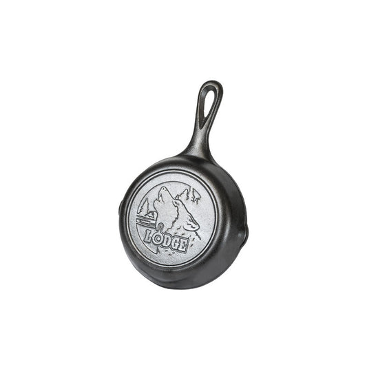 A 6.5 inch cast iron skillet with a howling wolf design on the bottom and a mountain range with the brand 'Lodge' engraved on the lid.