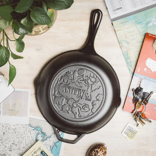 Black cast iron skillet with 'United States of America' engraving on a surface with maps and keys.