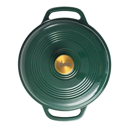 A green Lodge cast iron Dutch oven shown from a top-down view, featuring a circular lid with concentric ridges, two side handles, and a gold-colored center knob with the Lodge logo.