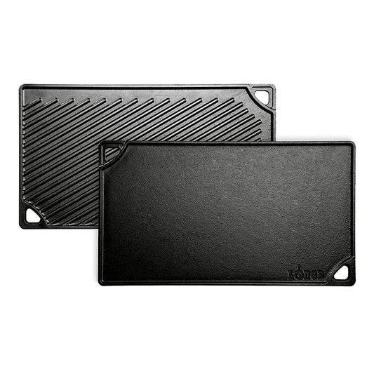 Two black reversible grill/griddle pans, one with a ribbed surface and the other with a smooth surface, both with handles.