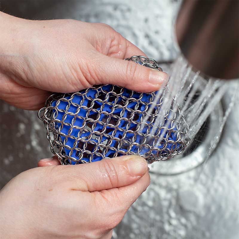Scrubber being rinsed under running water.