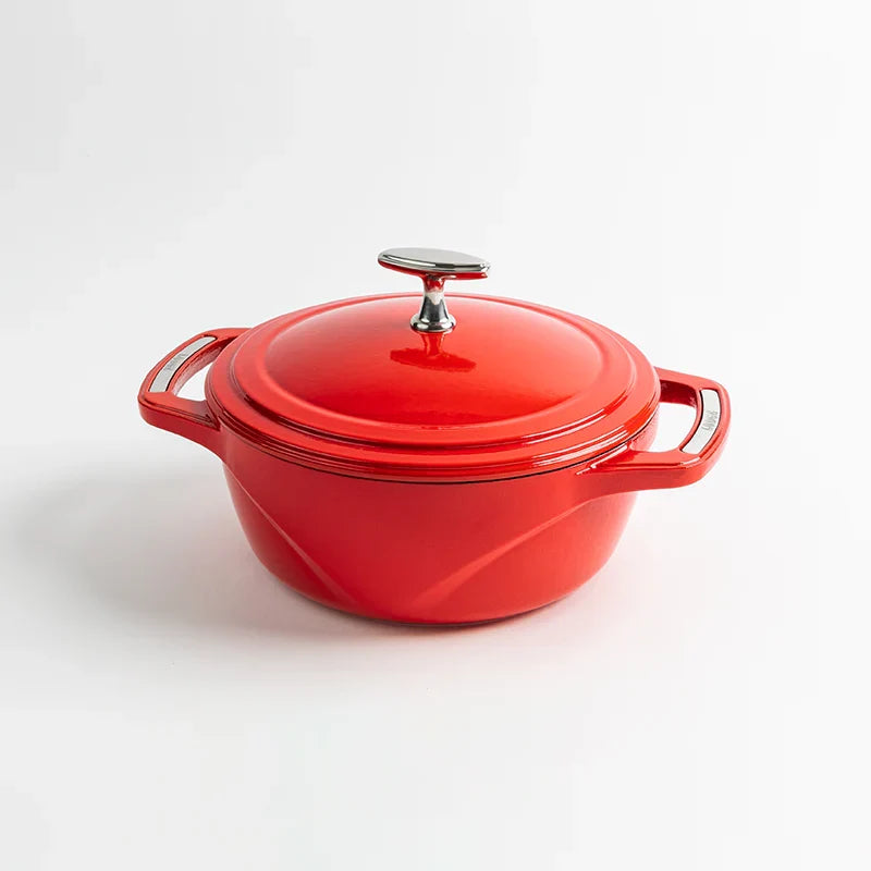 Red enameled cast iron Dutch oven with a lid on a white background