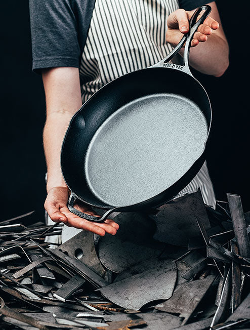 Someone holding skillet over pieces of metal.