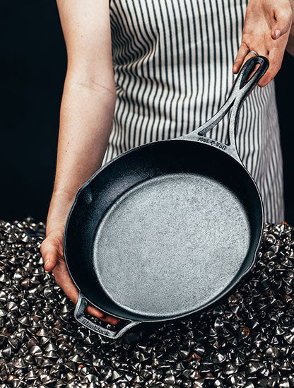 Someone holding skillet in front of a pile of ground iron.
