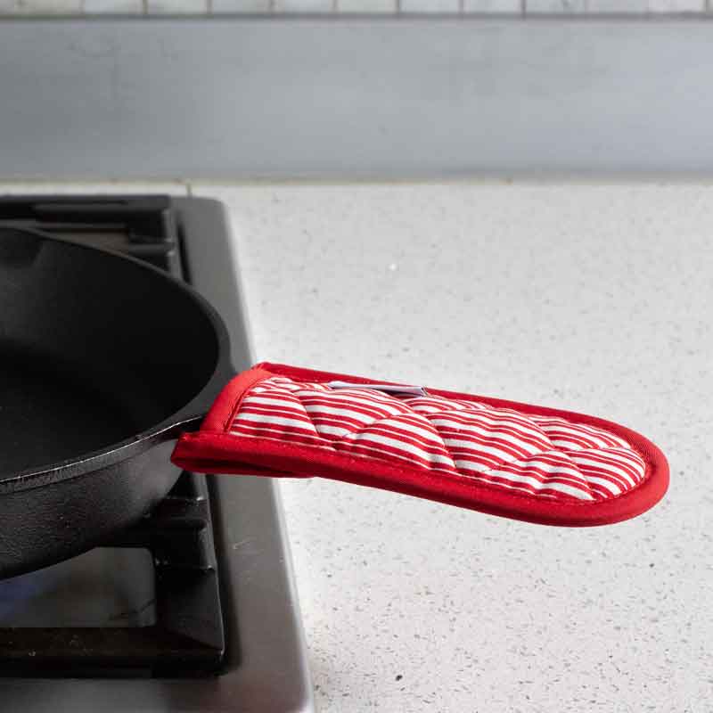 Handle holder being used on skillet on stove.