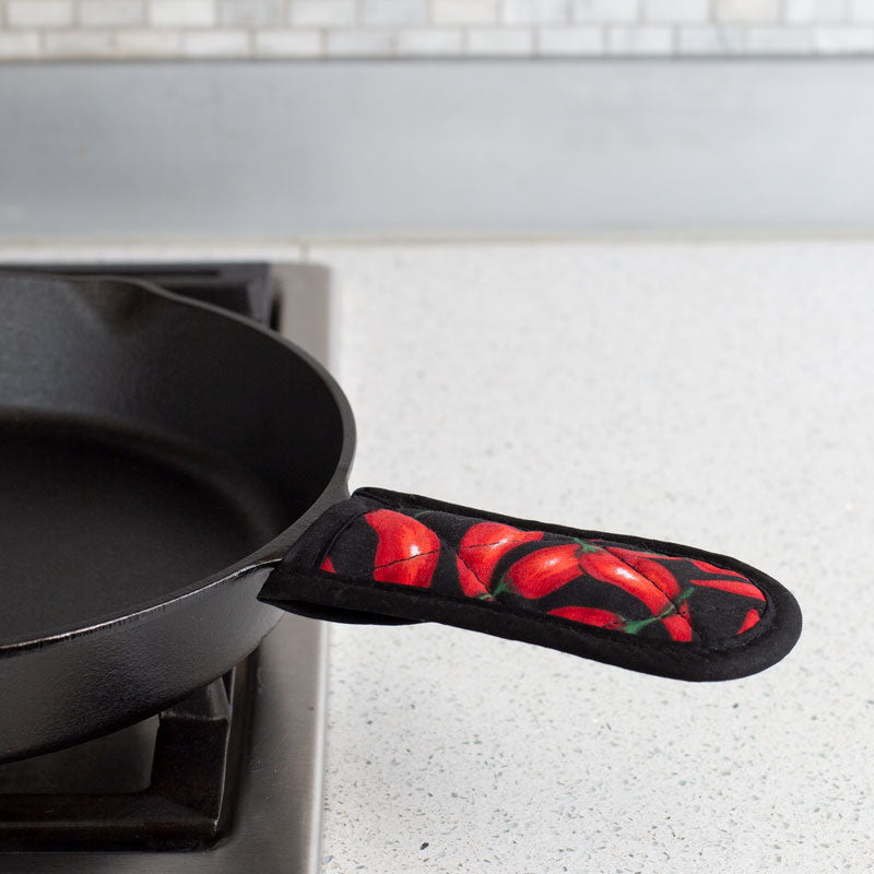 Handle holder being used on skillet on stove.
