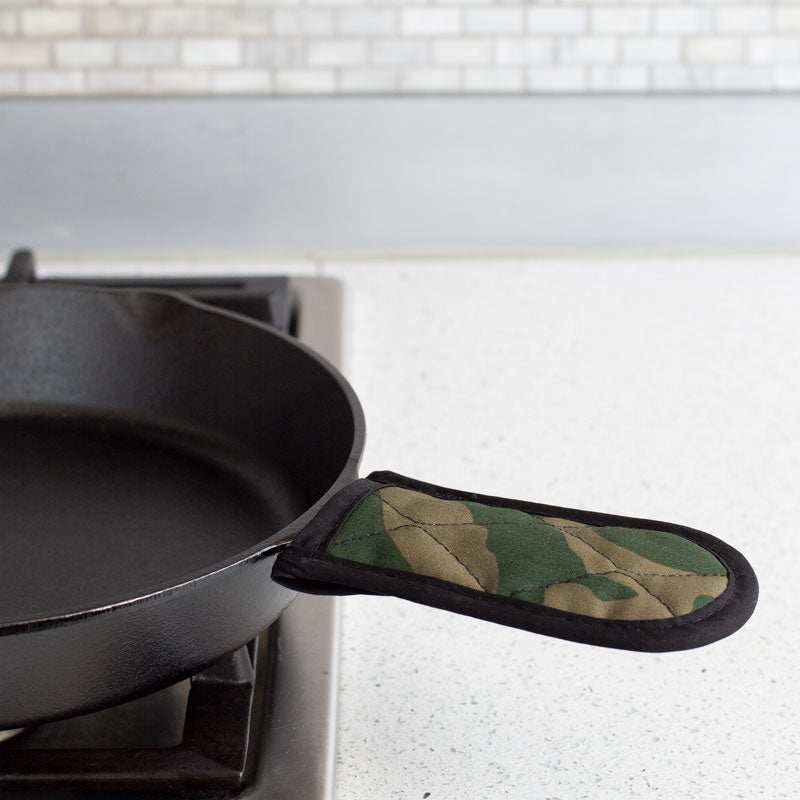 Handle holder being used on skillet on stove.