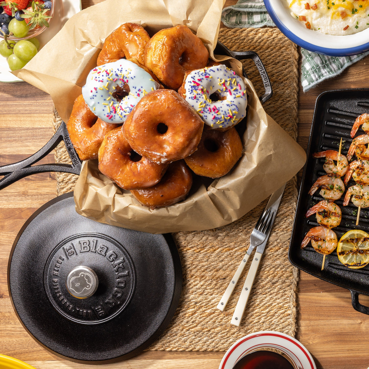 Top view of kitchen table filled with dishes including donuts prepared in skillet.