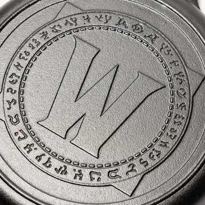 Close-up of World of Warcraft logo on the bottom of a cast iron skillet.