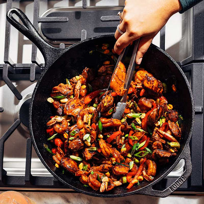 Top view of someone mixing chicken and shrimp stir fry in wok.
