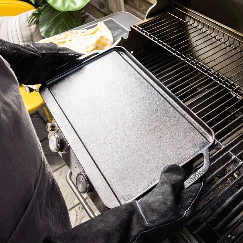 Person using a cast iron griddle on a grill