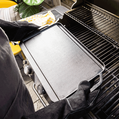 Person using a cast iron griddle on a grill