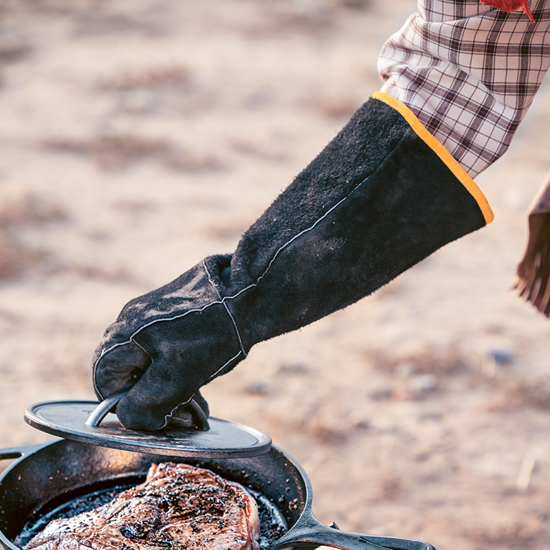 Someone wearing glove while using press on steak.
