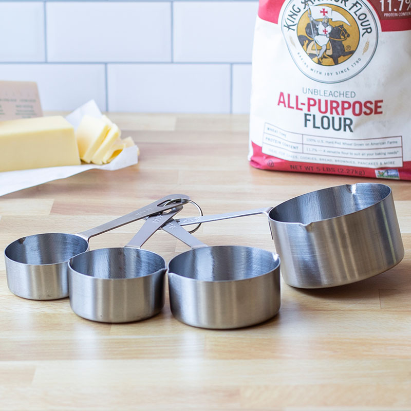 Measuring cups spread out on counter beside flour.