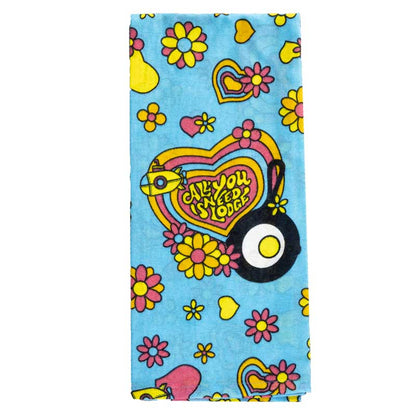 Close-up of twoel showing colorful floral and heart pattern with text "All you need is Lodge" in the middle of a large heart next to the skillet and egg Lodge logo.