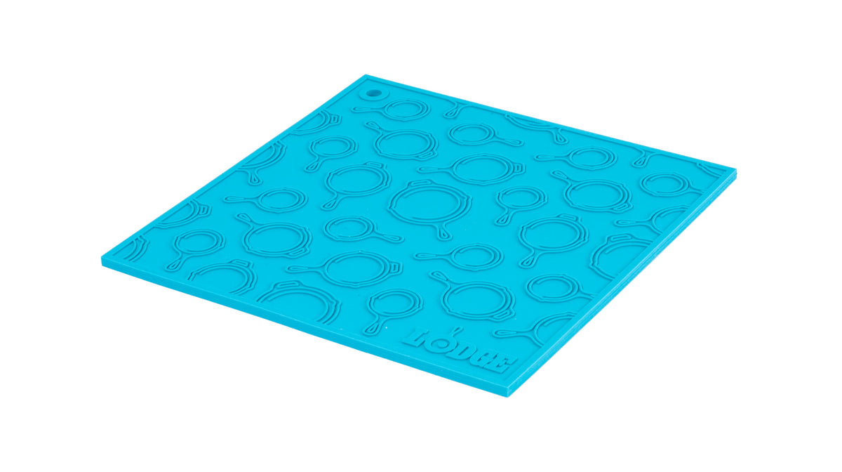 Turquoise silicone trivet with embossed Lodge skillets scattered throughout surface.