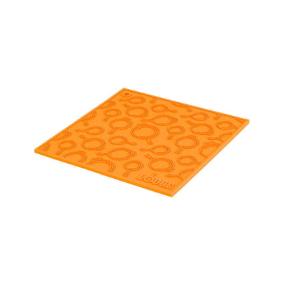 Orange silicone trivet with embossed Lodge skillets scattered throughout surface.