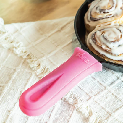 Pink handle holder used to hold a skillet full of freshly baked cinnamon rolls.
