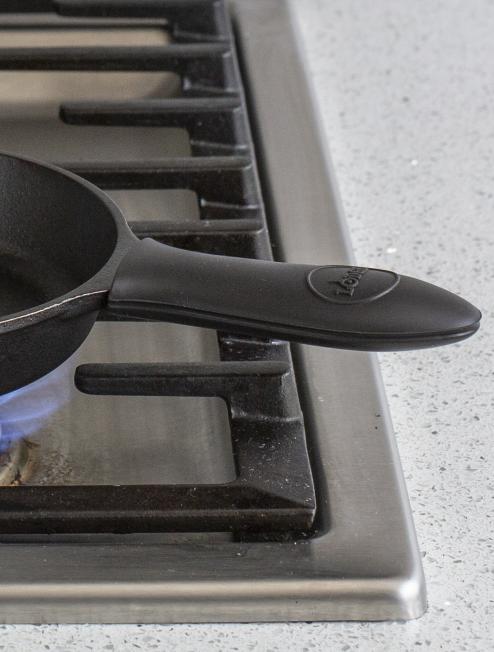 Silicone handle holder on skillet cooking on stove.