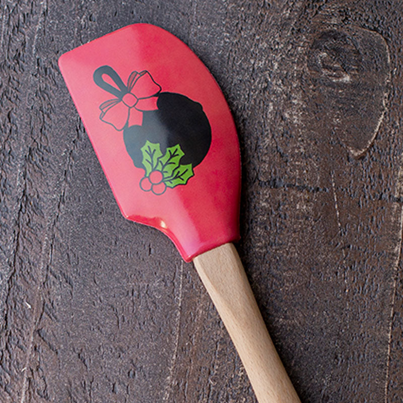 Close-up of design on spatula featuring a skillet with a bow behind mistletoe.