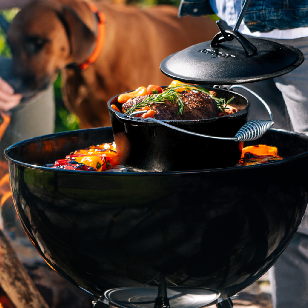 Beef chuck roast being prepared in dutch oven on grill.