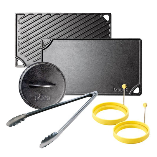 Cookware set with two reversible cast iron griddle and grill pans, a grill press, tongs, and silicone egg rings on a white background.