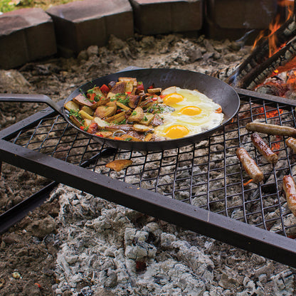 Eggs and potatoes being cooking outdoors with skillet.