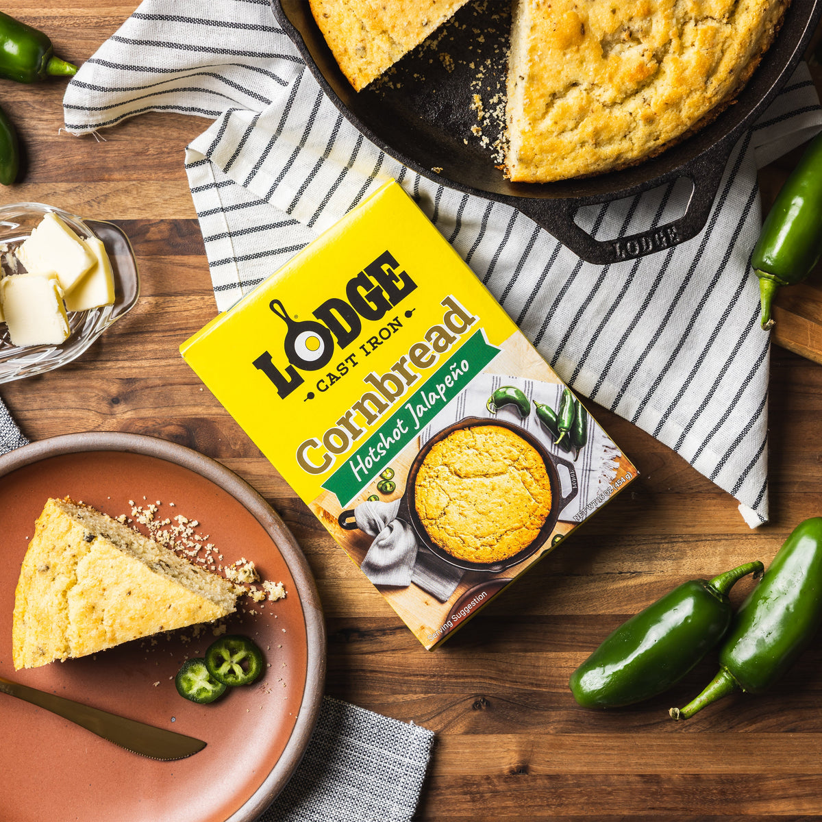 Lodge Hotshot Jalapeno Cornbread mix with cornbread on a plate and in a skillet on a wooden surface.