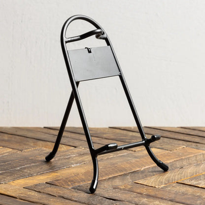 Black metal stand with a rectangular platform on a wooden surface
