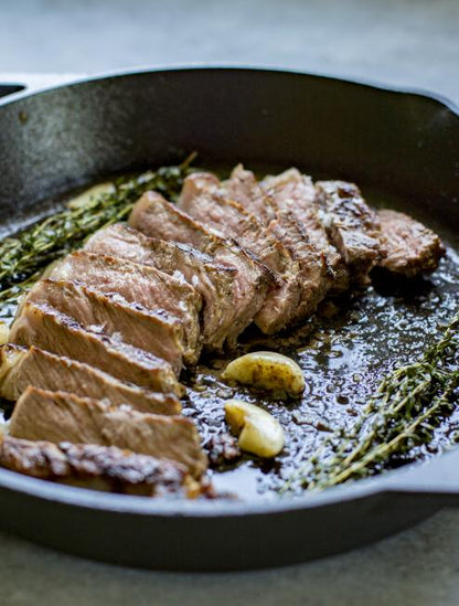 Freshly made steak served in pan with garlic and rosemary.