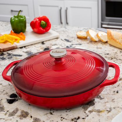 Braiser on kitchen counter in front of fresh peppers and sliced bread.