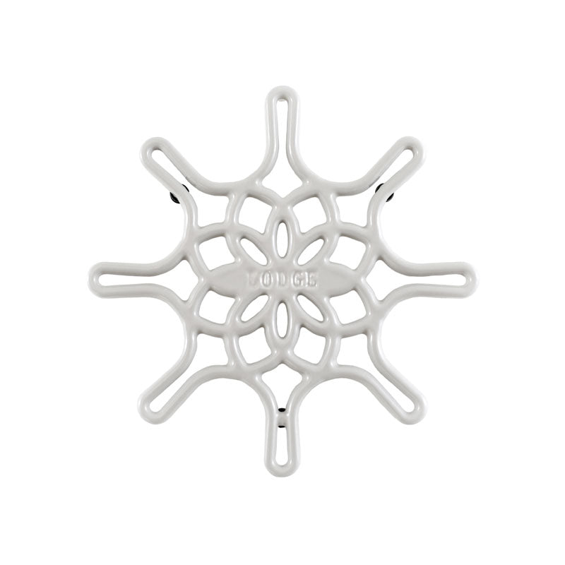 A white enameled cast iron trivet with a geometric snowflake-like pattern.