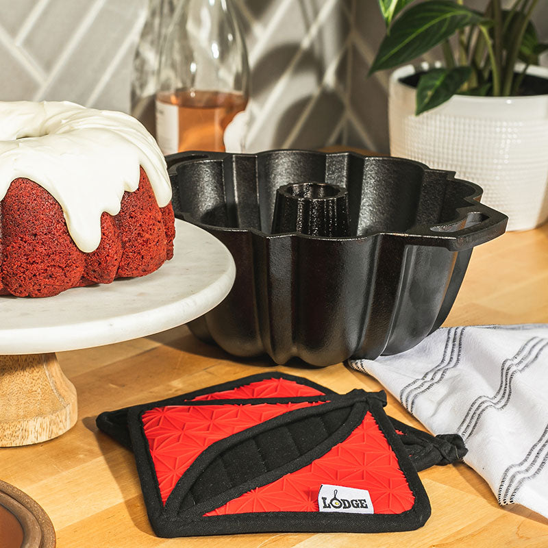 Pan and pot holder's near freshly baked and iced cake.