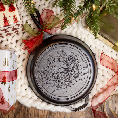 Cast iron skillet on a festive holiday background featuring the engraved Gnome design on back.