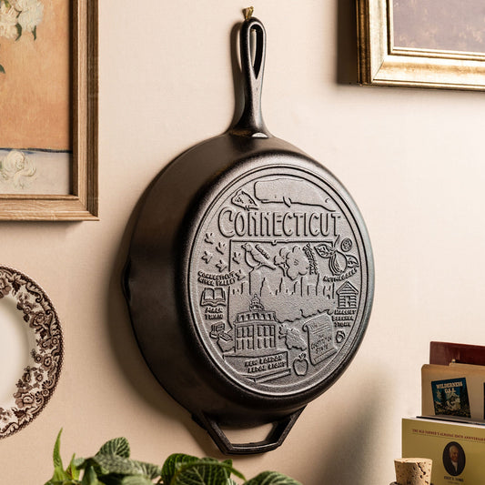 Black cast iron skillet with 'Connecticut' design displayed a wall.