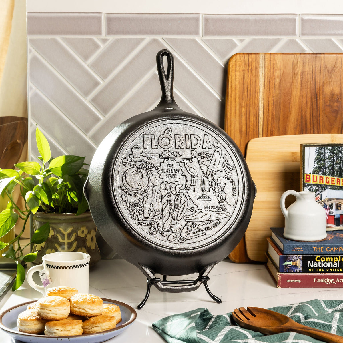 Cast iron skillet with 'Florida' engraving on a kitchen counter with books and a plant.