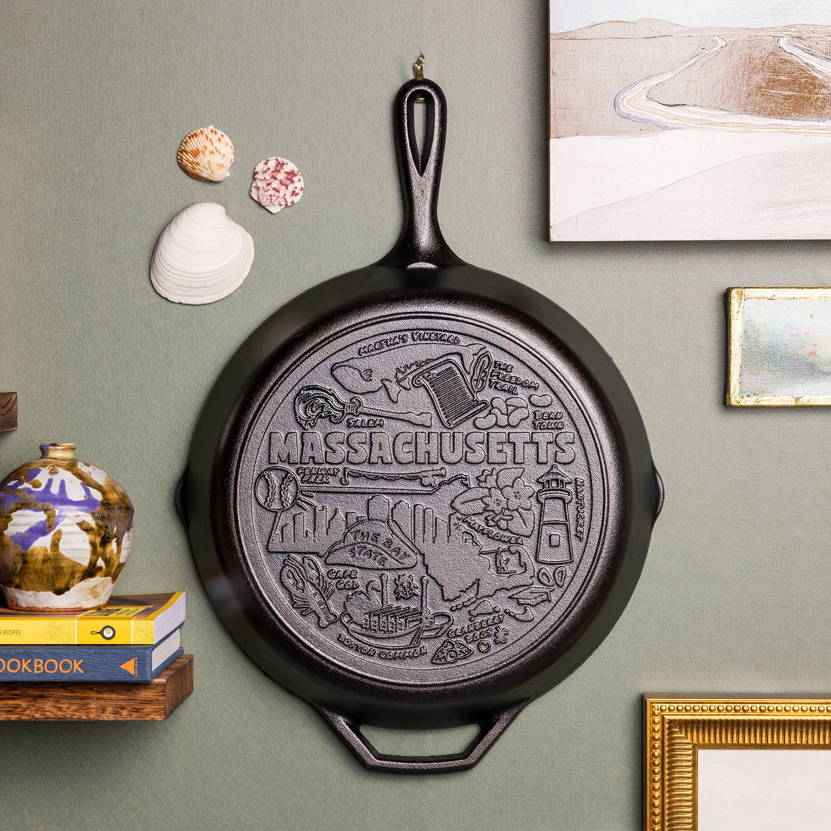 Black cast iron skillet with 'Massachusetts' engraving on a wall with decorative elements.