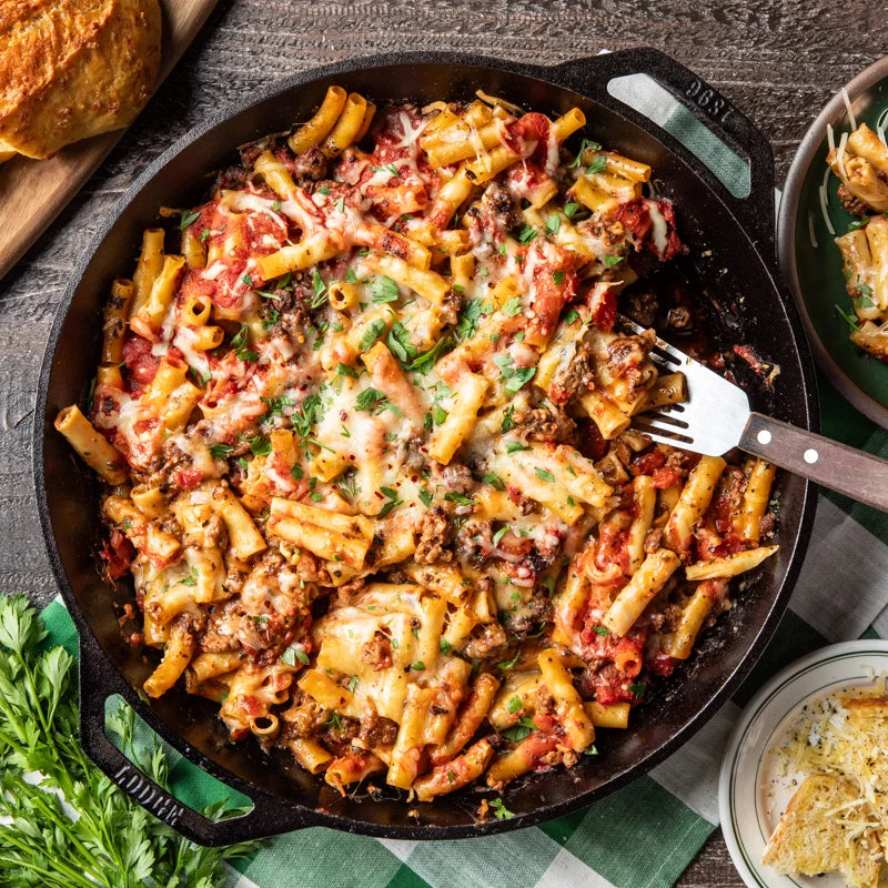 Pasta with melted cheese and red sauce being served from skillet.