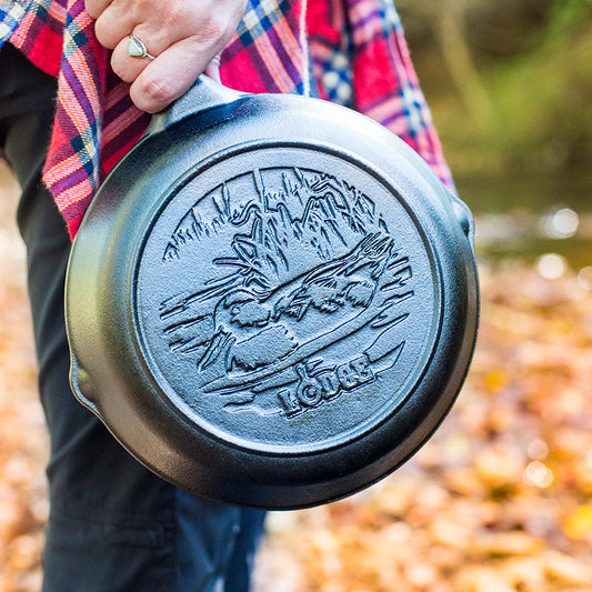 Person holding a cast iron skillet with an engraved swimming duck.