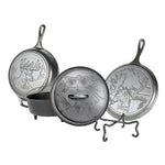 Set of a skillet, griddle, and camp dutch oven with animal designs, along with a tool for camp cooking.