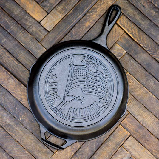 Black cast iron skillet with 'Made in America' and flag engraving on a wooden surface.