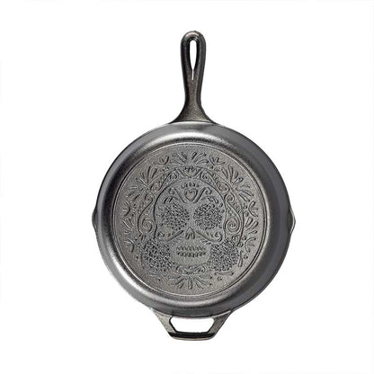 Black cast iron skillet with sugar skull design engraved on back.