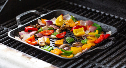 Veggies roasting in grill topper on grill.