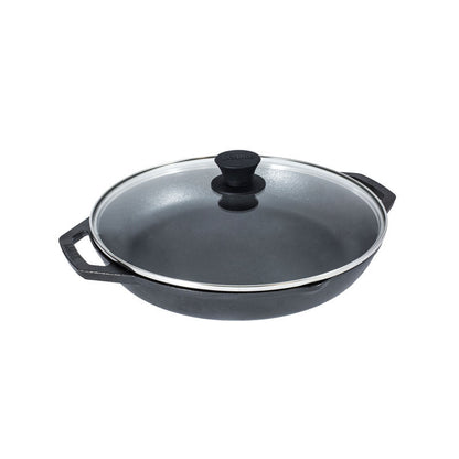 A dual handle cast iron pan with 2 pour spouts topped with a glass lid.