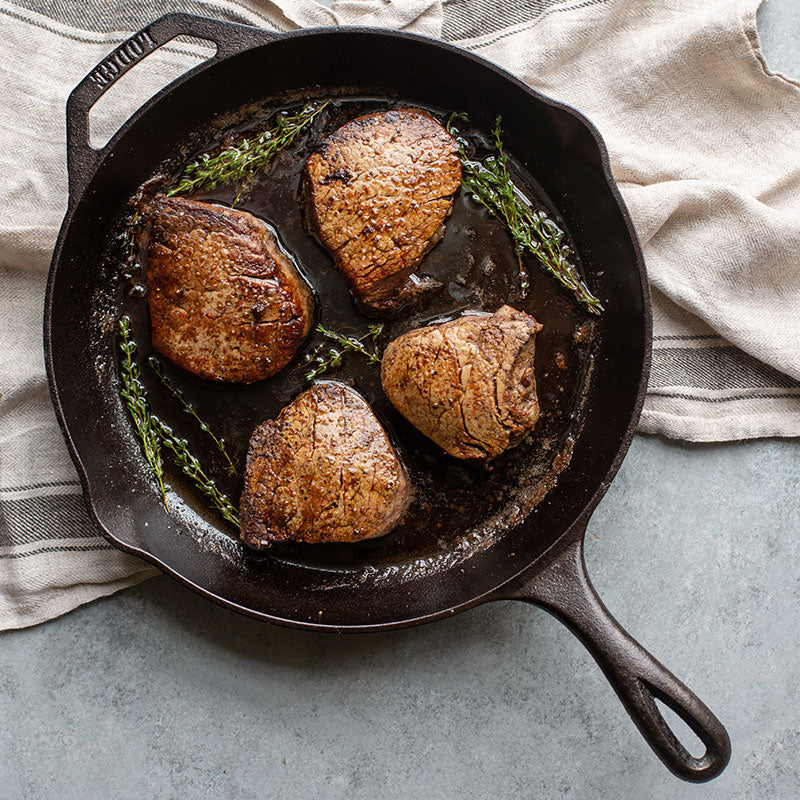 Filet mignon prepared in skillet, served on counter.