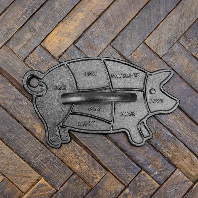 Cast iron pig-shaped press on a wooden surface.