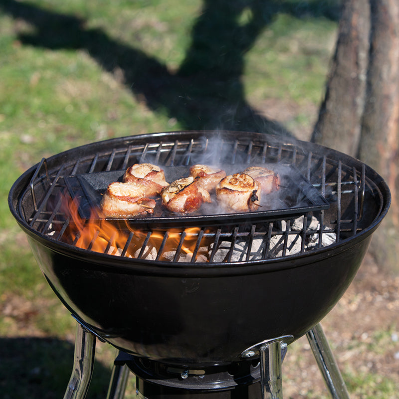 Scallops being cooked on griddle over charcoal grill.